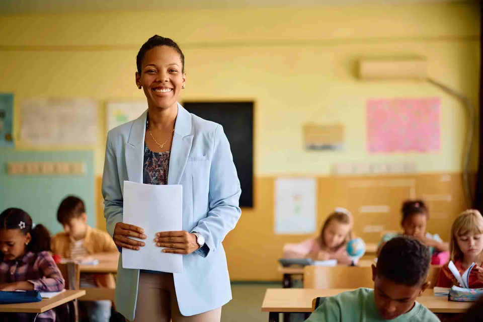 Smiling teacher standing among her pupils in a classroom