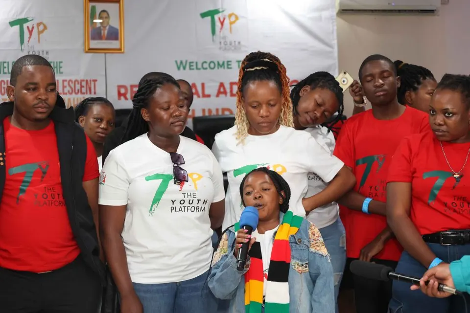 Young girl speaking into a microphone, surrounded by Youth Platform members